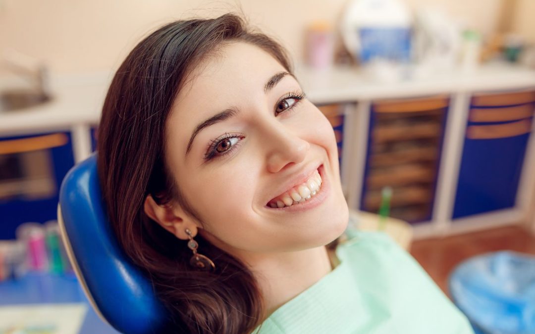 Smiling woman in dental chair at modern dental office during routine checkup or treatment.